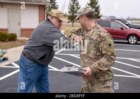 Sgt de l'armée américaine. Jeffrey Habeck, un soldat affecté à la 1-148ème Infantry Regiment de la Garde nationale de l’Ohio – 37ème équipe de combat de la Brigade d’infanterie, bosse les coudes avec un volontaire à l’église communautaire de Waterville après avoir livrer des aliments de la Toledo Northwestern Ohio Food Bank à Tolède, Ohio, le 24 mars 2020. Près de 400 membres de la Garde nationale de l’Ohio ont été activés pour fournir des missions humanitaires à l’appui des efforts de secours DE COVI-19, poursuivant la longue histoire de la Garde nationale de l’Ohio, qui a soutenu les efforts humanitaires dans l’ensemble de l’Ohio et de la nation. (ÉTATS-UNIS Photo de la Garde nationale aérienne par Airman K Banque D'Images