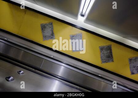 Escalator à angle aigu avec des murs en tuiles apparentes, un espace vide où les affiches ont été retirées d'une peinture jaune à Kings Cross Station Sydney Banque D'Images