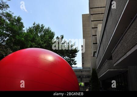 Une énorme boule rouge est installée comme expositions d'art public entre les bâtiments du centre-ville de Toronto. Banque D'Images