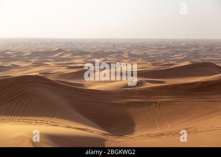 Dunes de sable du désert avec des traces de roues de voiture. Banque D'Images