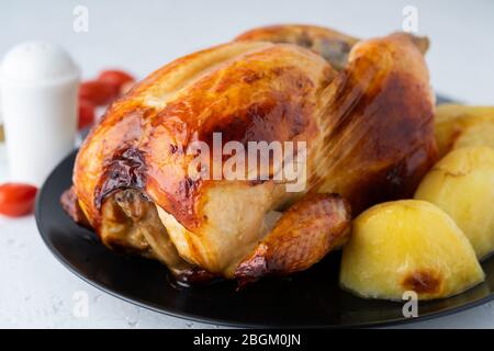 Poulet entier grillé en plaque noire sur table blanche, viande cuite avec pommes de terre. Vue latérale, gros plan Banque D'Images