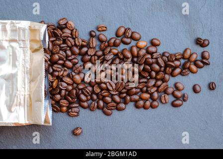 Emballage de café, grains saupoudrés, fond sombre. Arabica Banque D'Images