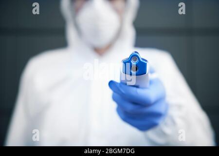 Technicien en costume propre tenant un thermomètre sans contact Banque D'Images