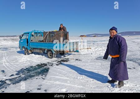 KHATGAL, MONGOLIE, 27 février 2020 : les hommes ont creué un trou dans la glace du lac gelé pour pomper l'eau. Banque D'Images