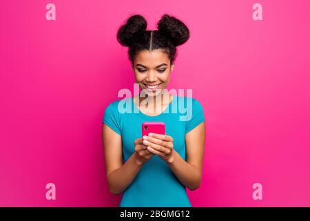 Photo de jolie jeune fille de peau sombre dame deux petits pains tenir les mains téléphone lecture blog commentaires reposts feedback porter bleu décontracté t-shirt isolé Banque D'Images