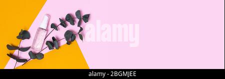 Un sanitazer naturel. Fond jaune et rose, gel transparent dans un pot entouré d'eucalyptus. Banque D'Images