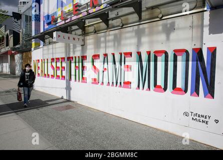 Vancouver, Canada. 21 avril 2020. Un résident fait des promenades devant une fresque peinte sur un magasin embarqué devant une rue du centre-ville de Vancouver, Canada, le 21 avril 2020. Une quarantaine d'artistes ont participé à une campagne « oural for Hope » en créant des peintures murales sur les magasins embarqués du quartier du centre-ville afin d'apporter espoir et positivité au milieu de la pandémie COVID-19. Crédit: Liang Sen/Xinhua/Alay Live News Banque D'Images