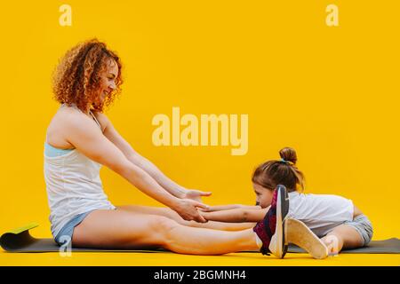 Mère aimant MHppy et fille faisant des exercices physiques sur fond jaune Banque D'Images