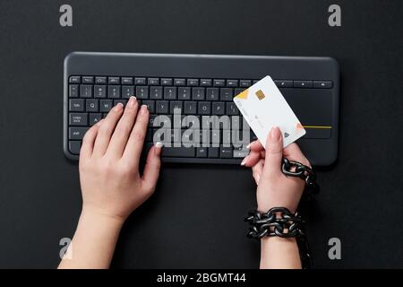 Femme avec chaîne de métal tenant la carte de crédit sur le clavier, concept de dépendance de shopping en ligne Banque D'Images