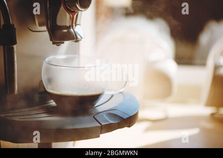 Machine à café qui verse du café expresso chaud dans une tasse. Banque D'Images