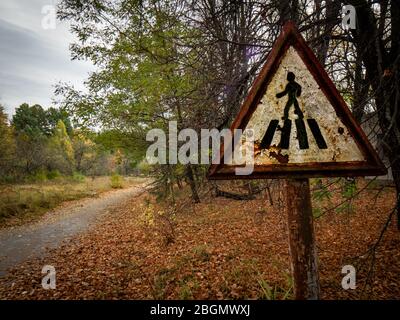 Ancien panneau de signalisation rouillé pour piétons dans la zone d'exclusion de Tchernobyl et inutilisé depuis la catastrophe ancienne route. Ukraine Banque D'Images