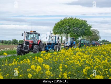 Pocklington, Yorkshire, Royaume-Uni, 24/05/2015 - une gamme de tracteurs multicolores qui conduisent le long d'une voie nationale. Banque D'Images