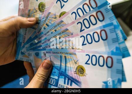 Un fan de billets de banque de 2000 roubles russes à la main d'un jeune homme. Banque D'Images