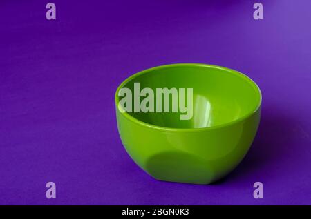 Bol en céramique vert sur fond lilas. Videz le bol pour soupe ou salade. Ustensiles de cuisine. Gros plan. Mise au point sélective. Banque D'Images