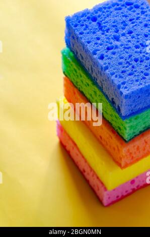 Éponges poreuses de cuisine. Une pile d'éponges de cuisine multicolores sur fond jaune. Un jeu de nouveaux accessoires lumineux pour le nettoyage. clea commercial Banque D'Images