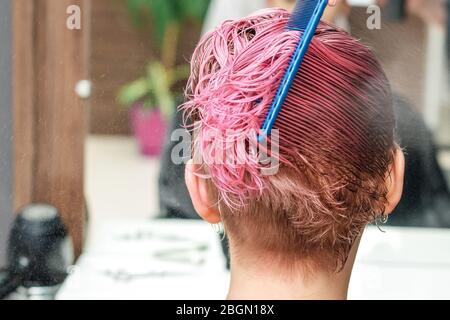 Les mains de coiffeur saupoudrer d'eau sur les cheveux roses de la femme dans le salon de coiffure. Banque D'Images