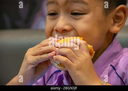 Poisson de hamburger dans la main asie garçon tenant la nourriture. Banque D'Images