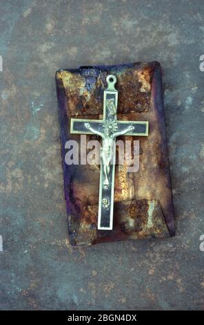 Crucifix en laiton et en ébène posé sur des blocs de bois et de lin tachés et brûlés Banque D'Images