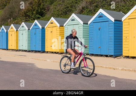 Bournemouth, Dorset, Royaume-Uni. 22 avril 2020. Météo au Royaume-Uni : belle journée chaude et ensoleillée, les températures montent sur les plages de Bournemouth sur la côte sud, les gens s'exerçant avec leur autorisation, en respectant la plupart des directives du coronavirus. Jeune cycliste cycliste le long de la promenade, après les cabanes de plage - vélo d'équitation. Crédit : Carolyn Jenkins/Alay Live News Banque D'Images