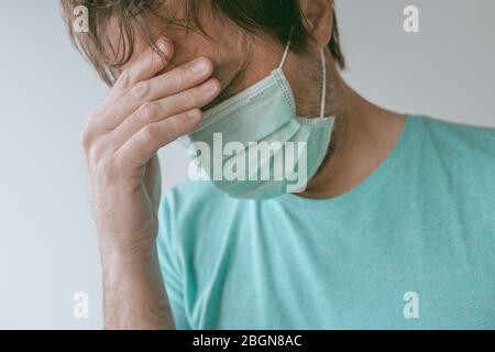 Homme avec masque ayant des maux de tête de migraine comme symptômes de Covid-19, portrait de homme avec infection virale pendant les pandémies Banque D'Images