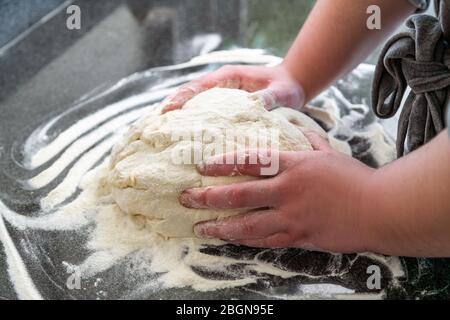 Gros plan du chef préparant la pâte pour la cuisson du pain ou de la pizza. Pâte blanche ronde faite à la main sur une table de cuisine Banque D'Images