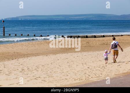 Bournemouth, Dorset, Royaume-Uni. 22 avril 2020. Météo au Royaume-Uni : belle journée chaude et ensoleillée, les températures montent sur les plages de Bournemouth sur la côte sud, les gens s'exerçant avec leur autorisation, en respectant la plupart des directives du coronavirus. Homme et tout-petit marchant sur la plage. Crédit : Carolyn Jenkins/Alay Live News Banque D'Images