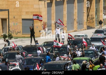 Beyrouth, Liban. 22 avril 2020. Les manifestants portant des masques de protection se présentent sur la place Martyr à Beyrouth lorsqu'ils prennent part à un convoi de voitures avec des conducteurs qui se marient avec leurs cornes, Agitant le drapeau national libanais et se penchant sur les vitres de la voiture pour protester contre la détérioration du niveau de vie, y compris la hausse des prix et du chômage exacerbés depuis que le gouvernement a imposé des mesures de verrouillage sévères pour lutter contre la propagation du coronavirus covid-19. Crédit: amer ghazzal/Alay Live News Banque D'Images