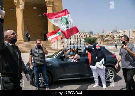 Beyrouth, Liban. 22 avril 2020. Les manifestants portant des masques de protection se présentent sur la place Martyr à Beyrouth lorsqu'ils prennent part à un convoi de voitures avec des conducteurs qui se marient avec leurs cornes, Agitant le drapeau national libanais et se penchant sur les vitres de la voiture pour protester contre la détérioration du niveau de vie, y compris la hausse des prix et du chômage exacerbés depuis que le gouvernement a imposé des mesures de verrouillage sévères pour lutter contre la propagation du coronavirus covid-19. Crédit: amer ghazzal/Alay Live News Banque D'Images