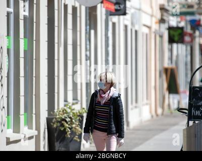 Potsdam, Allemagne. 22 avril 2020. Une femme portant un masque et des gants est en regardant les écrans de fenêtre dans le centre commercial Brandenburger Straße. Les petites boutiques peuvent rouvrir dans le Brandebourg, les magasins de 800 mètres carrés d'espace de vente aussi dans les centres commerciaux ainsi que les concessionnaires de voitures, de vélos et de livres sont parmi eux. Crédit: Soeren Stache/dpa-Zentralbild/ZB/dpa/Alay Live News Banque D'Images