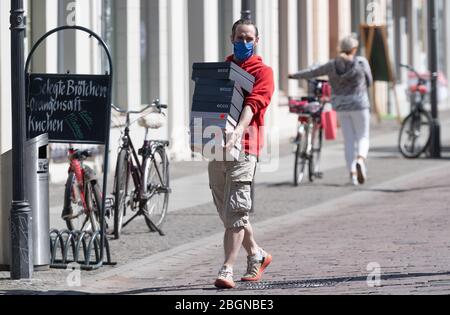 Potsdam, Allemagne. 22 avril 2020. Un employé de la boutique de chaussures 'Schuh Baar' porte des cartons de chaussures dans la rue commerçante Brandenburger Straße. Les petites boutiques peuvent rouvrir dans le Brandebourg, les magasins de 800 mètres carrés de zone de vente sont également inclus dans les centres commerciaux, ainsi que les concessionnaires de voitures, de vélos et de livres. Crédit: Soeren Stache/dpa-Zentralbild/ZB/dpa/Alay Live News Banque D'Images