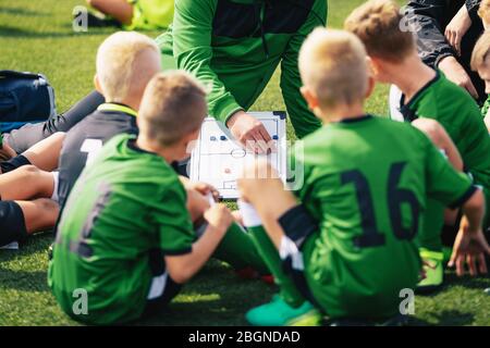 Jeunes garçons dans l'équipe de football à l'écoute de l'entraîneur. Coach donnant des instructions à son équipe de football pour enfants. Tournoi de football. Compétition de football scolaire. Coac Banque D'Images