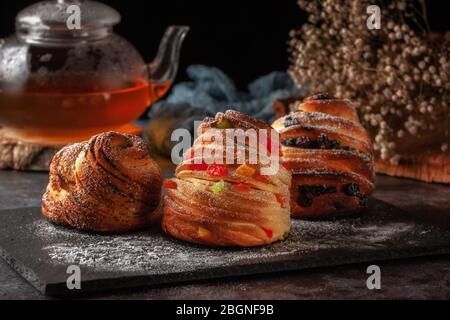 Kraffins aux raisins secs, fruits confits et graines de pavot, arrosés de sucre en poudre. Banque D'Images