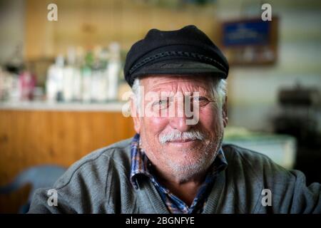 Homme local âgé portant un chapeau plat dans un café du village de Dhrousha, d'Akamas Heights, à Chypre Banque D'Images