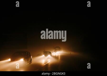 Bourrage de circulation dans la fumée. Lumière des phares de voiture dans la fumée du feu Banque D'Images