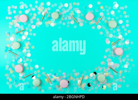 Plat festif avec confetti en papier rond coloré, bougies dorées et macarons sur fond de menthe tendance. Concept d'anniversaire heureux. Banque D'Images