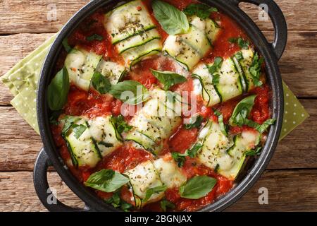 Petits pains courgettes cuits au four avec du fromage ricotta et des herbes dans une sauce tomate dans une poêle sur la table près du haut. Vue de dessus horizontale Banque D'Images