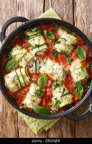 Rouleau de courgettes farci de ricotta et cuit dans la sauce tomate dans une poêle sur la table près. Vue verticale du dessus Banque D'Images