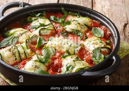 Apéritif chaud de courgettes cuites au fromage ricotta et aux herbes dans une sauce tomate dans une poêle sur la table. Horizontal Banque D'Images