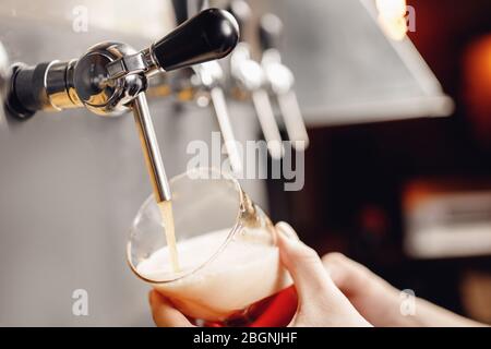 Barman verse la bière du robinet en verre, fond sombre. Alcool concept de boisson artisanale Banque D'Images