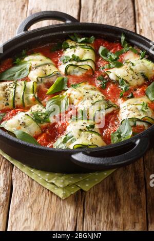 Les courgettes méditerranéennes sont cuites à la ricotta et aux herbes cuites dans une sauce tomate dans une poêle sur une table de gros plan. Vertical Banque D'Images