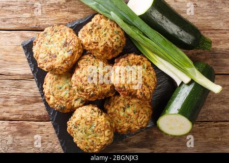 De délicieuses boulettes de courgettes grecques au fromage feta avec des ingrédients à proximité sur une planche en ardoise sur la table. Vue de dessus horizontale Banque D'Images