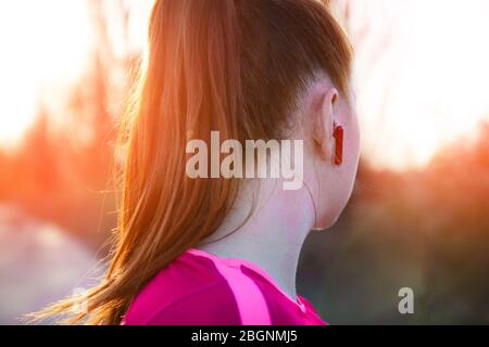 FAT girl avec casque sans fil court le long de la piste dans les rayons du soleil. Concept de perte de poids Banque D'Images