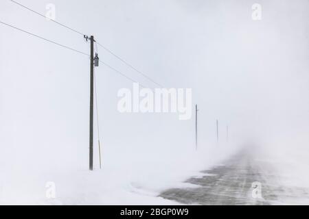 Neige qui souffle sur la neige sur la route près de Rudyard dans la partie orientale de la péninsule supérieure, Michigan, États-Unis Banque D'Images