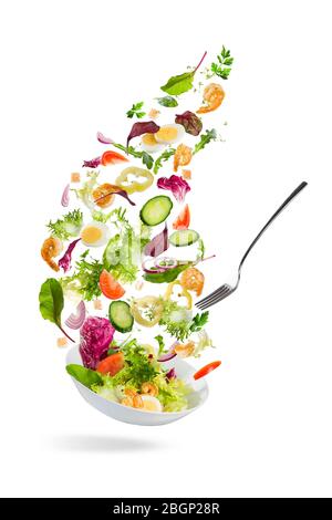 Légumes en tranches qui tombent dans un bol avec salade sur fond blanc
