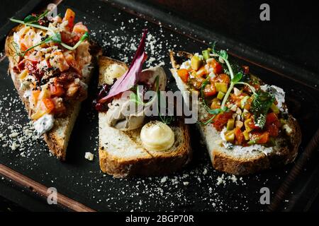 Délicieux bruschetta italienne avec tomate, pâtés de viande, olives, fromage à la crème. Ensemble de délicieux sandwichs appétissants. Banque D'Images