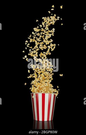 Volant de délicieux popcorn frais à partir d'un seau rayé en papier rouge et blanc isolé sur le fond noir. Pop-corn de style cinéma Banque D'Images