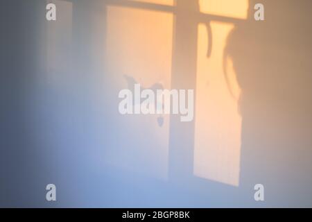 Un ange en bois avec un oreiller en forme de coeur dans une fenêtre au crépuscule Banque D'Images