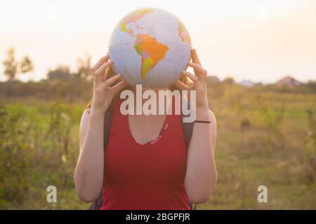 fille avec dos tenant globe dans fond de lumière de coucher de soleil Banque D'Images