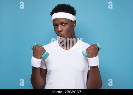 Jeune homme afro-américain souriant s'entraîner avec des haltères. Banque D'Images
