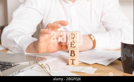 Homme d'affaires enlève des blocs de bois avec le mot dette. Réduction ou restructuration de la taxe. Annonce de faillite. Refus de payer des prêts et invalider Banque D'Images